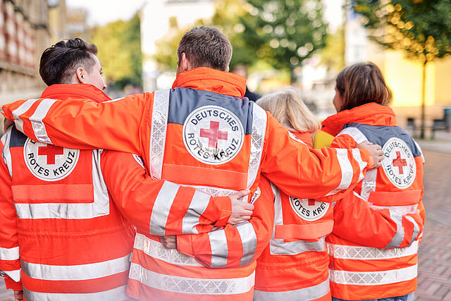 Symbolfoto, Team des DRK in Einsatzjacken, Ansicht von hinten